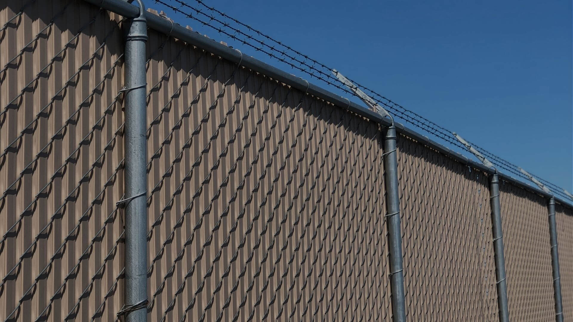 Chain link security fence with privacy slats and barbed wire topping, providing enhanced perimeter protection for commercial and industrial properties in Stockton, CA
